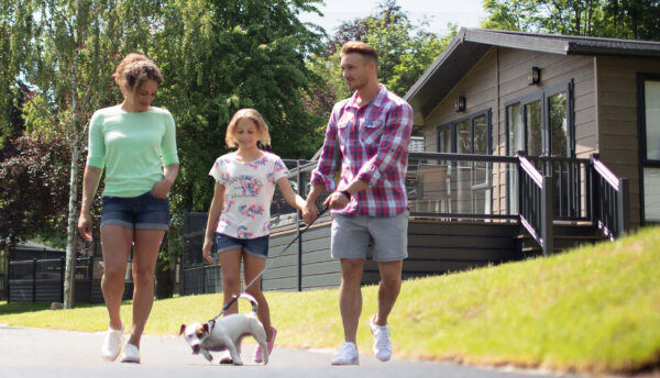 Family walking at Aysgarth with small dog and lodges in the background