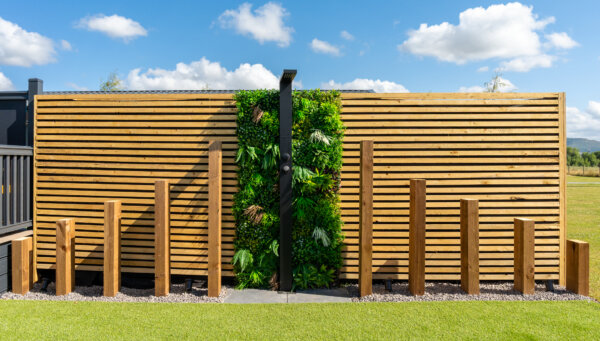 outdoor shower wall with wooden panelling and foliage wall